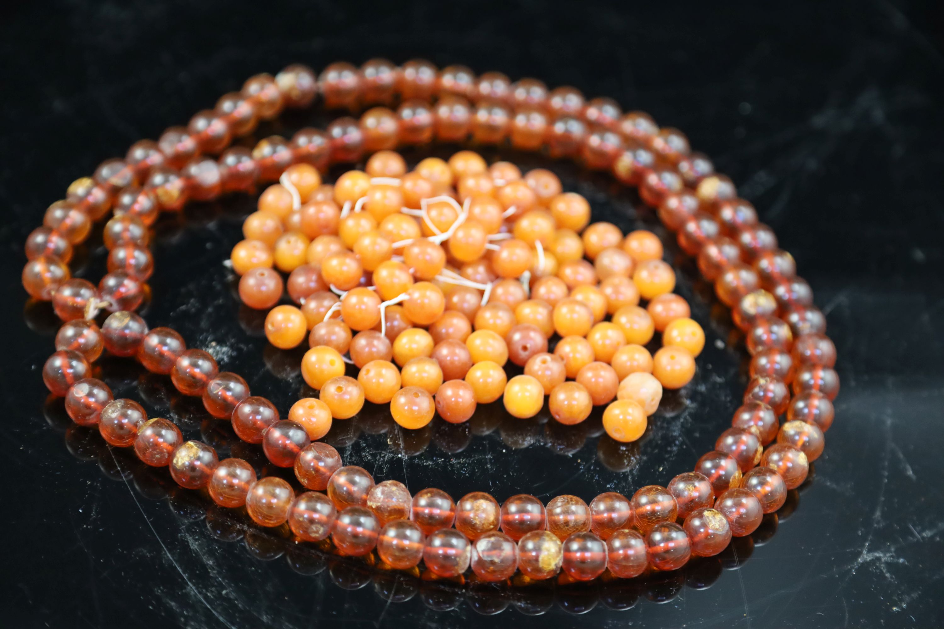 A single strand translucent amber bead necklace, 132cm, gross 153 grams and one other amber necklace (now loose), gross 126 grams.